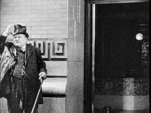 The same entrance to the bank appears during this scene from Charlie Chaplin's The New Janitor (1914).