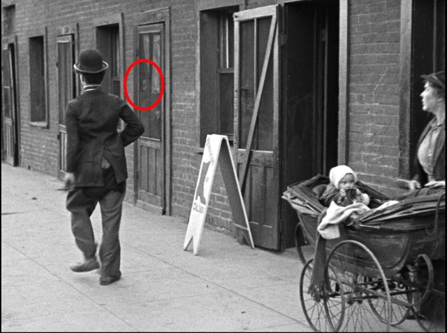 Click to enlarge. A delighted girl peeks through a screen door during The Kid.